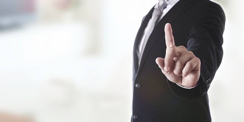 指を差すスーツ男性